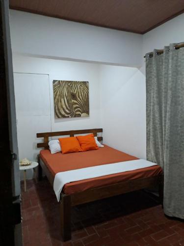 1 dormitorio con 1 cama con almohadas de color naranja en Hostel Casa Mar en Liberia