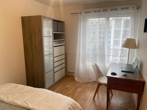 um quarto com uma secretária, um computador portátil e uma cama em 3 pièces avec belle terrasse et vue dégagée. em Suresnes