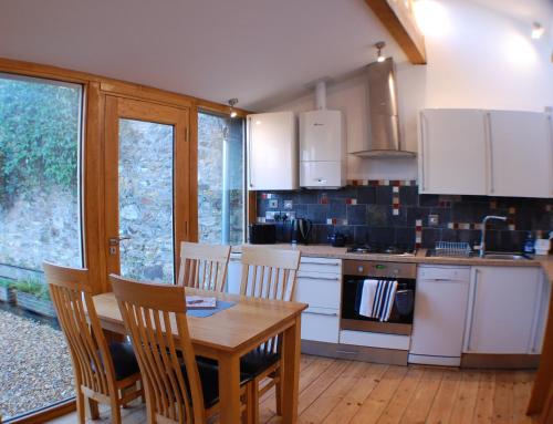 uma cozinha com uma mesa de madeira, uma mesa e cadeiras em The Stable - rural retreat, perfect for couples em Taunton