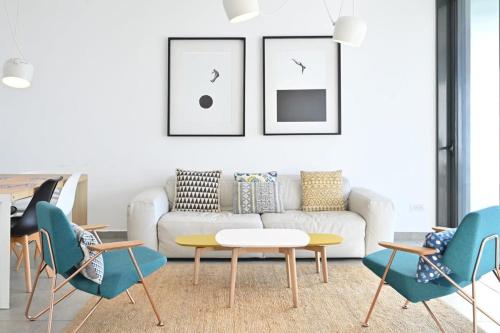 ein Wohnzimmer mit einem weißen Sofa und blauen Stühlen in der Unterkunft Yellow blue by HolyGuest in Tel Aviv