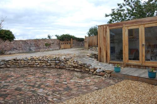 a garden with a stone wall and a wooden building at The Stable - rural retreat, perfect for couples in Taunton