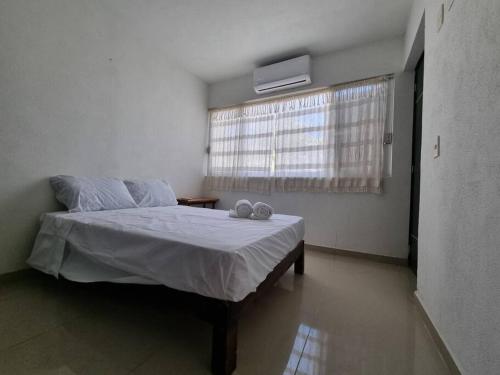 Un dormitorio con una cama y una ventana con dos zapatos. en Melaque Rent House 1, en San Patricio Melaque