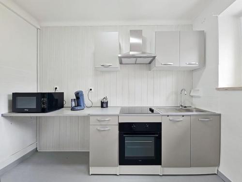 a white kitchen with a sink and a microwave at Appartement 2 chambres aux pieds des Vosges in Abreschviller