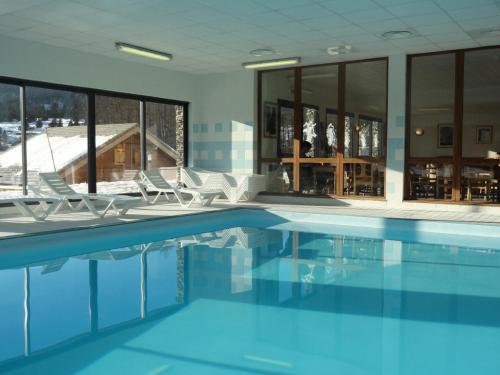 a swimming pool with chairs and a building at Résidence Le Hameau Du Puy - Chalets pour 6 Personnes 874 in Le Dévoluy