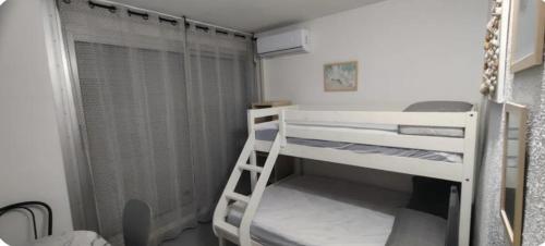 Cette petite chambre dispose de lits superposés et d'une échelle. dans l'établissement Studio a la mer piscine wifi parking clim, à La Grande Motte