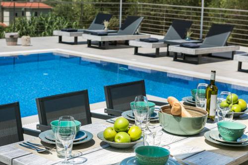 a table with a plate of food next to a pool at Escape Villa Kefalonia in Lourdhata