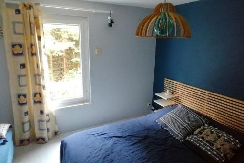 a blue bedroom with a bed and a window at Grande maison au charme chaleureux hiver comme été in La Bourboule