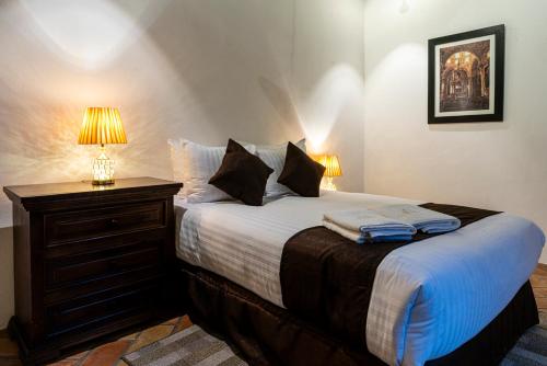a bedroom with a bed with a dresser and a lamp at HOTEL BOUTIQUE CASONA 65 in Puebla