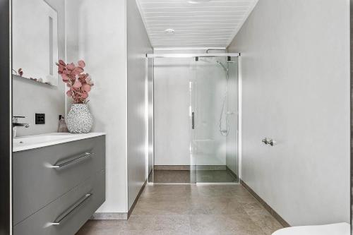 baño blanco con ducha y lavamanos en Egersund Overnatting, en Egersund