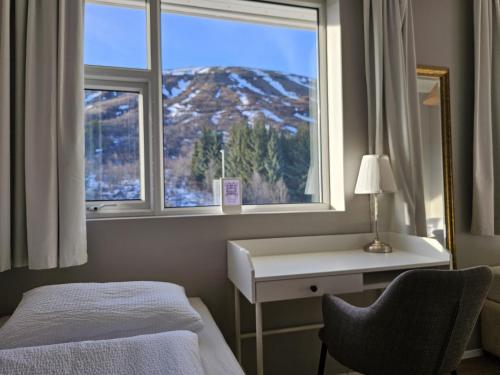 a room with a bed and a desk and a window at Hótel Laugarvatn in Laugarvatn