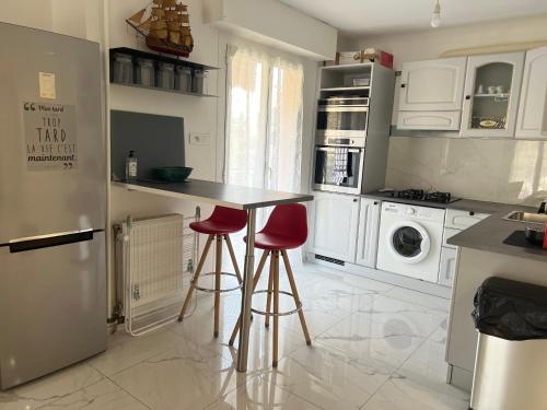 une cuisine avec un comptoir et deux tabourets de bar rouge dans l'établissement La chataigneraie, à Menton