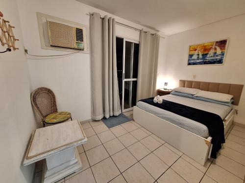 1 dormitorio con 1 cama, 1 silla y 1 ventana en Piratas Residence, en Angra dos Reis