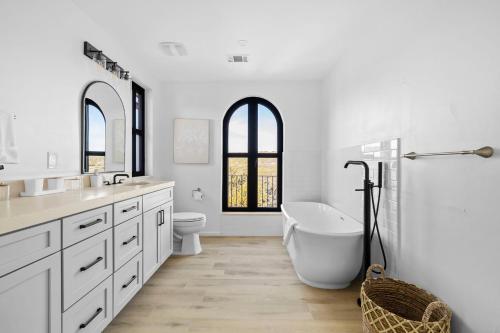 a white bathroom with a tub and a toilet at Las Luces in Spicewood