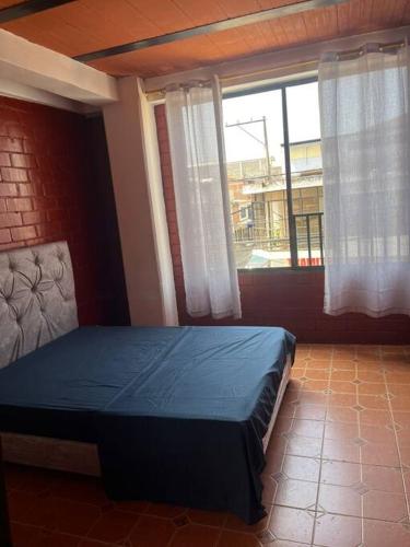 um quarto com uma cama azul e uma janela em Aparta estudio Jamundí em Potrerito