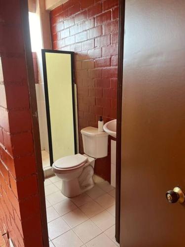a bathroom with a toilet and a brick wall at Aparta estudio Jamundí in Potrerito