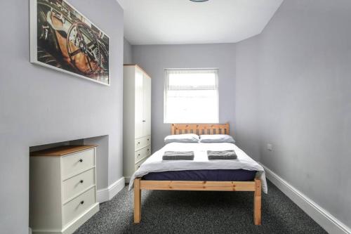 a bedroom with a bed and a dresser and a window at 5 bedroom house, free parking, near football, sleeps 8 in Liverpool
