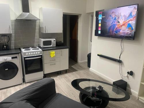 a kitchen with a living room with a tv on the wall at One bedroom Apartment in Cardiff City Centre in Cardiff