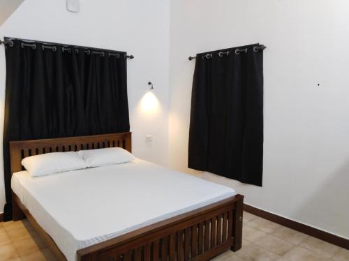 1 dormitorio con 1 cama con cortinas negras en The Chill House, en Kochi