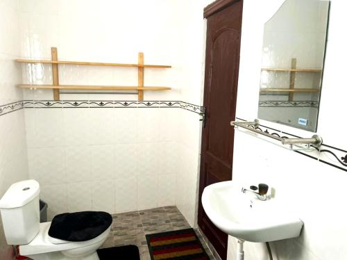 ein Badezimmer mit einem WC, einem Waschbecken und einem Spiegel in der Unterkunft Accra City Apartments in Accra