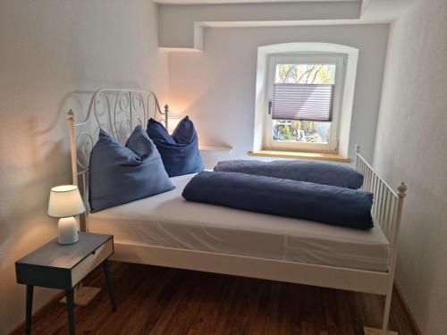 ein Schlafzimmer mit einem Bett mit blauen Kissen und einem Fenster in der Unterkunft Kapellenblick in Bad Häring