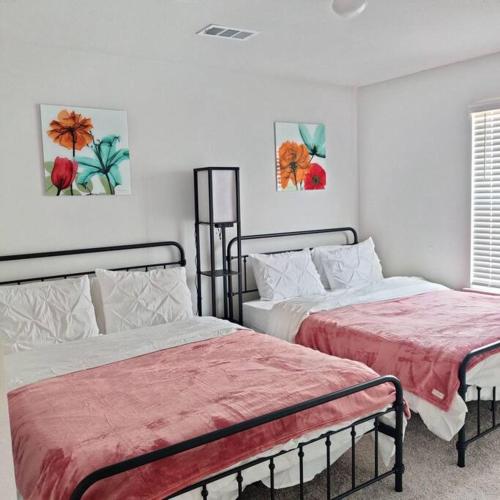 a bedroom with two beds and paintings on the wall at Maison EMN in Fort Worth