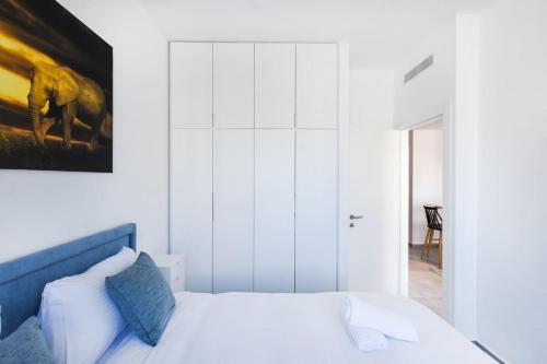 a bedroom with a white bed with a painting on the wall at Marine Pearl by HolyGuest in Tel Aviv