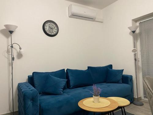- un canapé bleu dans le salon doté d'une horloge murale dans l'établissement Apartman Blagojevic, à Veliko Gradište