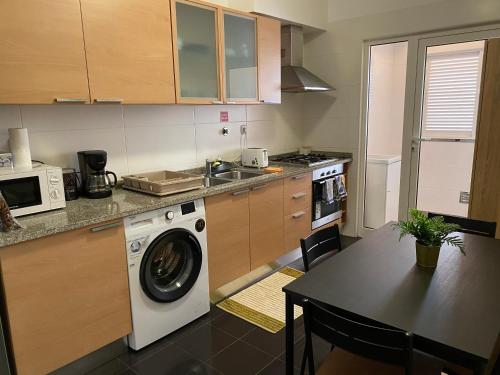 a kitchen with a washing machine and a table at Milagrosa Apartment in Caniço