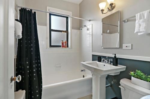 a bathroom with a sink and a tub and a toilet at Elegant 1-Bedroom Apartment in Hyde Park - Windermere 310 in Chicago