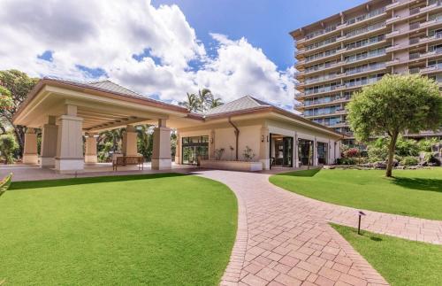 a house with a green lawn in front of a building at The Whaler By Maui Resort Rentals in Lahaina