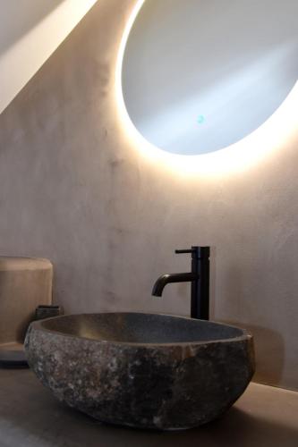 a bathroom with a stone sink with a light on the wall at Aegialis luxury apartments in Karistos