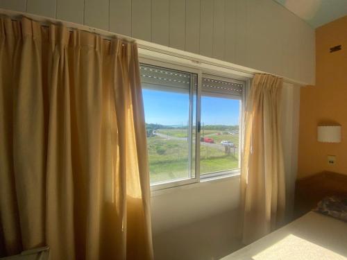 una ventana con cortinas entreabiertas en una habitación en Habitación frente al mar en Mar del Plata
