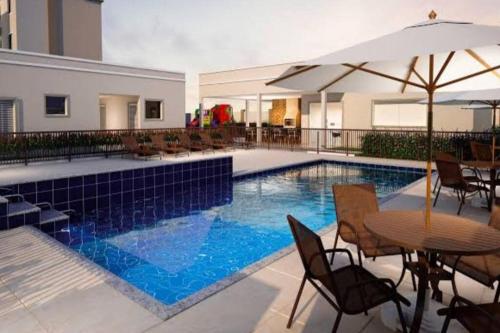 uma piscina com cadeiras e mesas e um guarda-sol em Apartamento inteiro litoral norte Natal RN em Natal