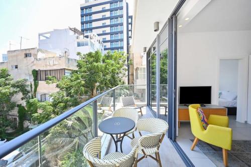 einen Balkon mit Stühlen, einem Tisch und einem TV in der Unterkunft New Day by HolyGuest in Tel Aviv