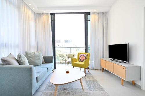 ein Wohnzimmer mit einem blauen Sofa und einem TV in der Unterkunft New Day by HolyGuest in Tel Aviv