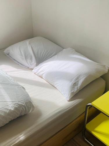 a bed with white sheets and pillows on it at Petite chambre sur cour aborée in Marseille