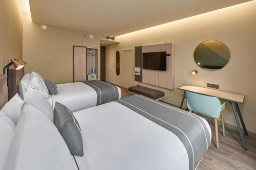 a hotel room with two beds and a tv at City Express Plus by Marriott Ensenada in Ensenada