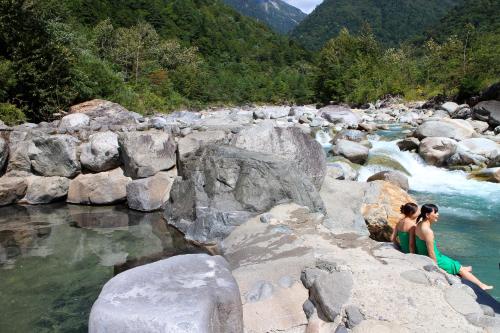 two women sitting on rocks in a river at Shinzanso in Takayama