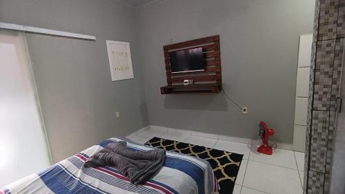 1 dormitorio con 1 cama y TV en la pared en Flat Nogueira, en Palmas
