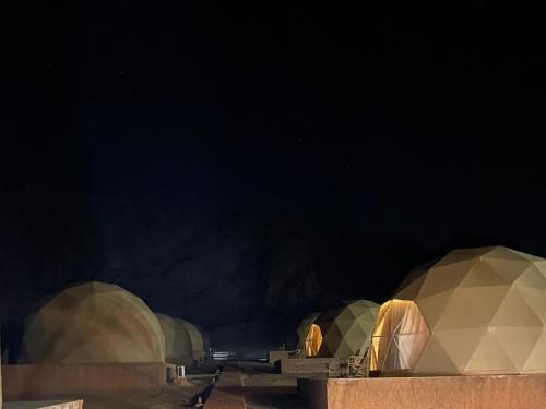 a group of domes in a desert at night at Wadi Rum Marcanã camp in Aqaba