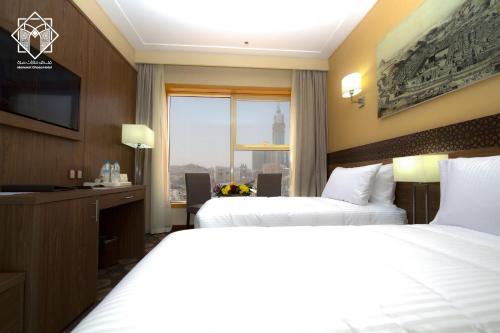 a hotel room with two beds and a television at Manarat Gaza Hotel - Al Haram Tower in Makkah