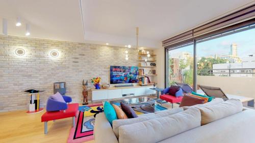 een woonkamer met een witte bank en rode stoelen bij Colorful Shenkin 3-BR by HolyGuest in Tel Aviv