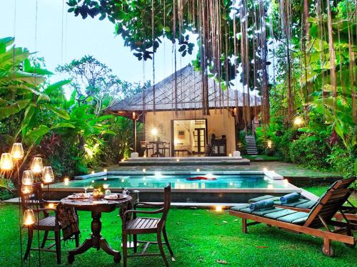 un patio trasero con piscina, mesa y sillas en Villa Canggu by Plataran, en Canggu