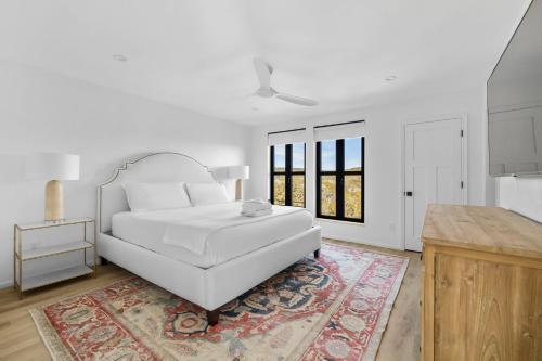 a white bedroom with a white bed and a rug at Las Luces in Spicewood