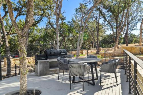 a patio with a table and chairs and trees at Las Luces in Spicewood