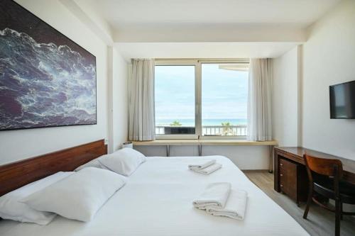 een slaapkamer met een groot wit bed en een raam bij Beach Front 2BR in Sea Hotel by HolyGuest in Tel Aviv