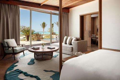 The St. Regis Red Sea Resort في Ḩanak: غرفة نوم مع سرير وغرفة معيشة