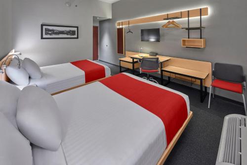 a hotel room with two beds and a desk at City Express by Marriott Matamoros in Matamoros