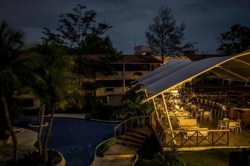 un complejo con piscina y un restaurante con mesas y sombrillas en Tower Suite Hotel Coronado, en Playa Coronado