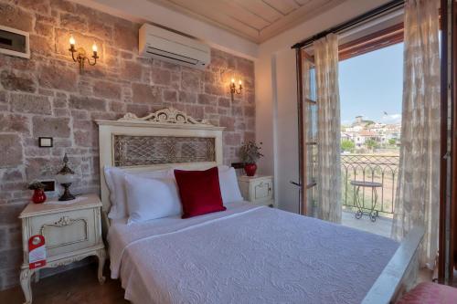 a bedroom with a white bed and a balcony at Tas Bahce Hotel Cunda in Ayvalık
